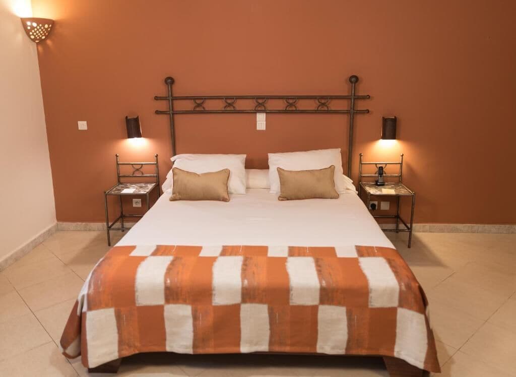 A bed with a checkered bedspread, two bedside tables with lamps, and a wall-mounted cross.