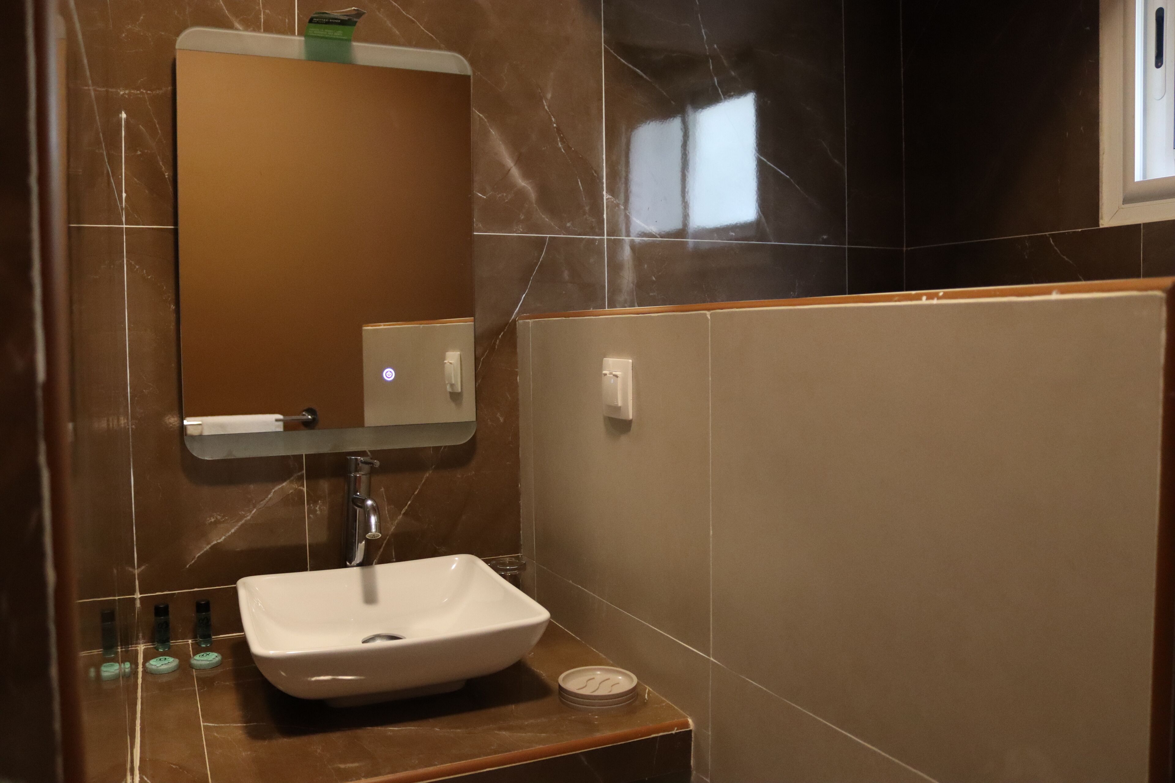 A bathroom with a white sink, a mirror, and a soap dispenser.