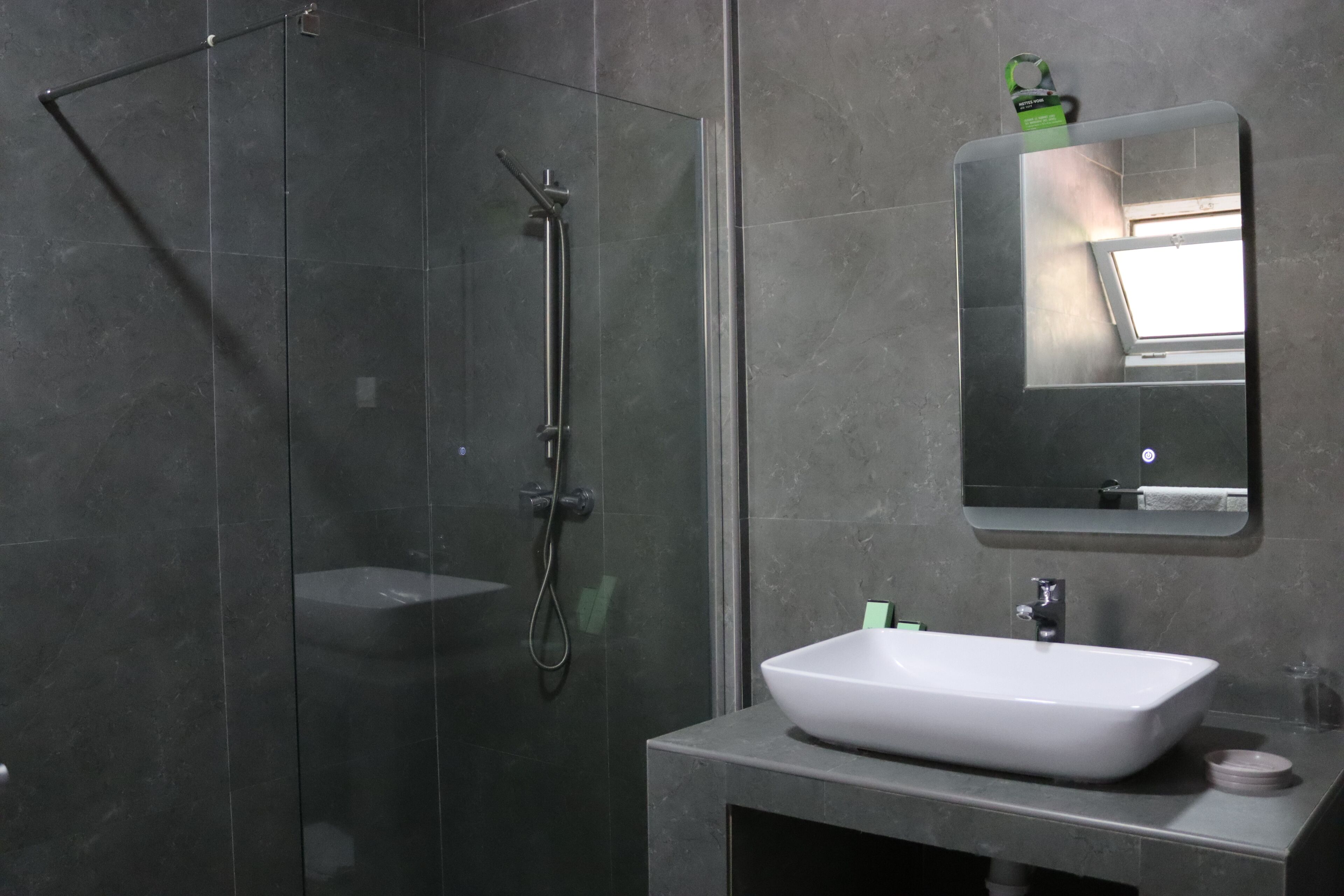 Une salle de bain moderne avec une douche à parois de verre, un lavabo blanc et un miroir au-dessus du lavabo.