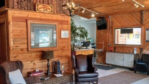 A cozy log cabin interior with a fireplace, wooden walls, a large window, and a comfortable seating area. - Lone Eagle Lodge (Grand Lake)