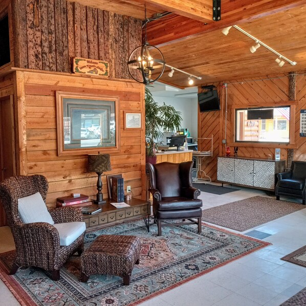 A cozy log cabin interior with a fireplace, wooden walls, a large window, and a comfortable seating area. - Lone Eagle Lodge (Grand Lake)