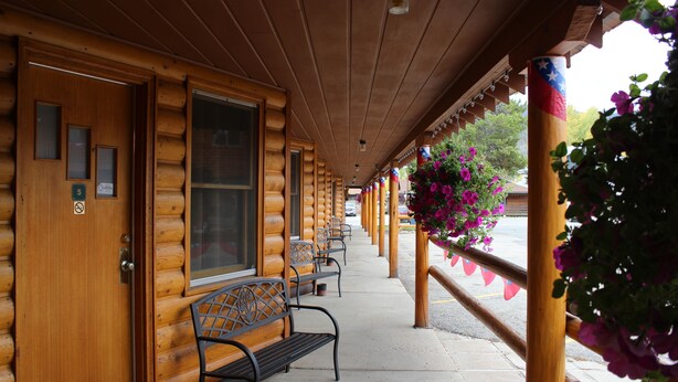A wooden cabin-style building with a covered porch, benches, and a row of windows. - Lone Eagle Lodge (Grand Lake)