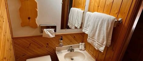 Un baño pequeño con tocador de madera, inodoro y lavamanos.
