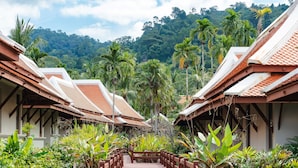 A pathway leading to a row of traditional-style buildings with red-tiled roofs, surrounded by lush tropical vegetation. - Khaolak Laguna Resort (Takua Pa)