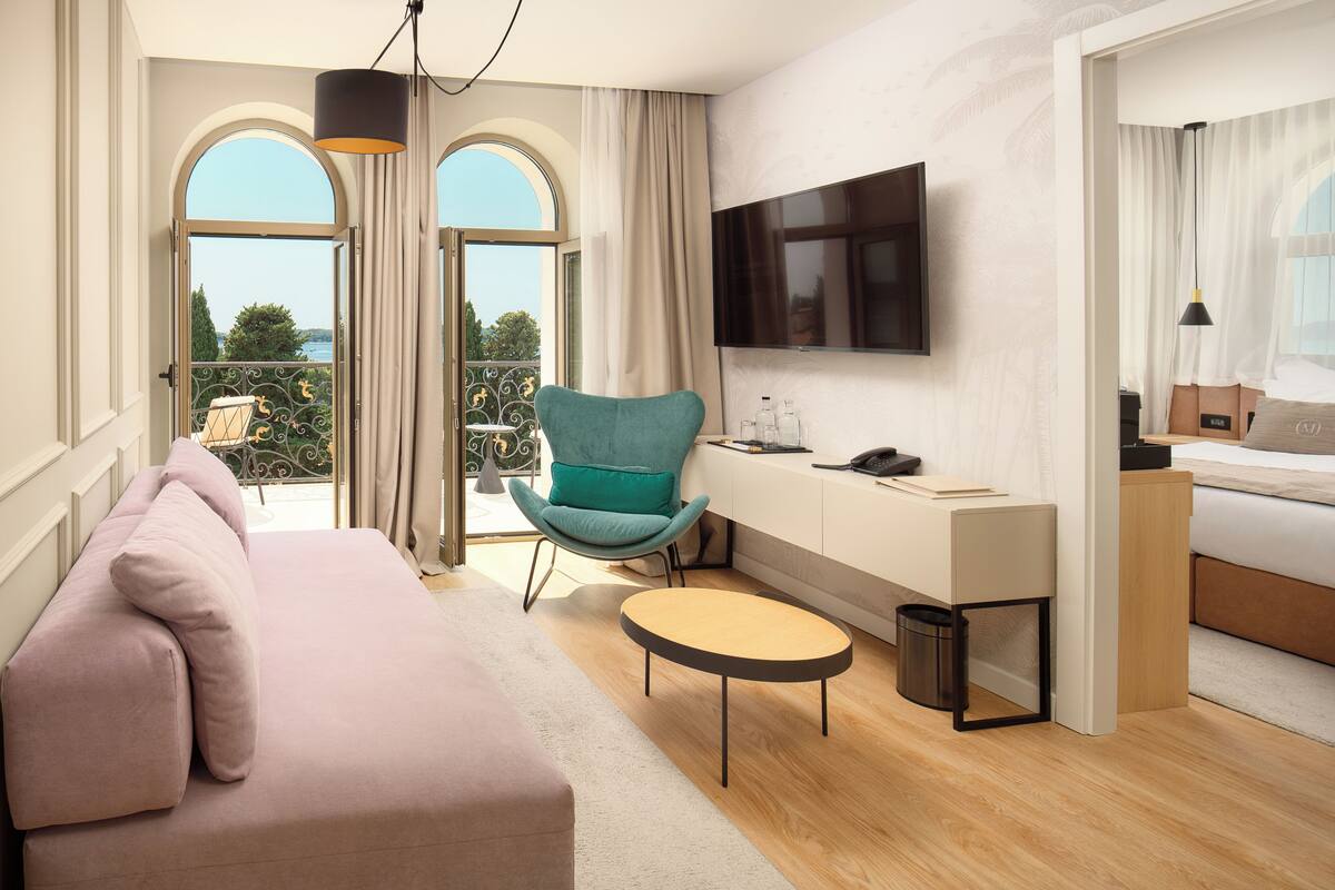 Una habitación de hotel moderna con un sofá, un escritorio con una silla, un televisor y una cama.