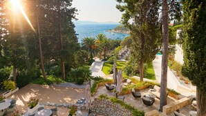 A patio area with outdoor seating, a stone wall, and a view of the sea.
