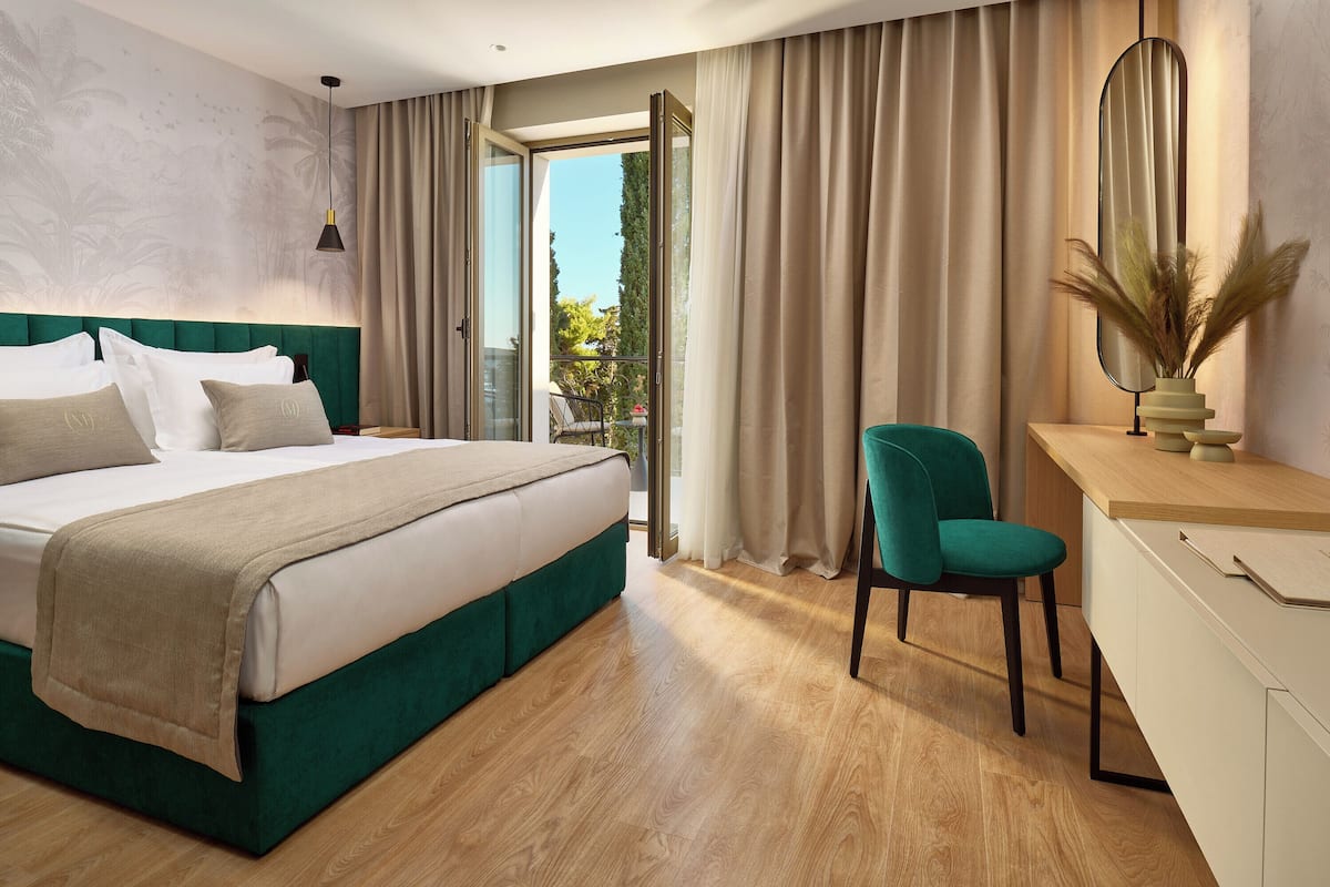 Habitación de hotel moderna con una cama grande, un escritorio y vistas al exterior.