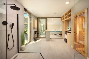 A modern bathroom with a glass shower enclosure, a potted plant, and a view of the outdoors.