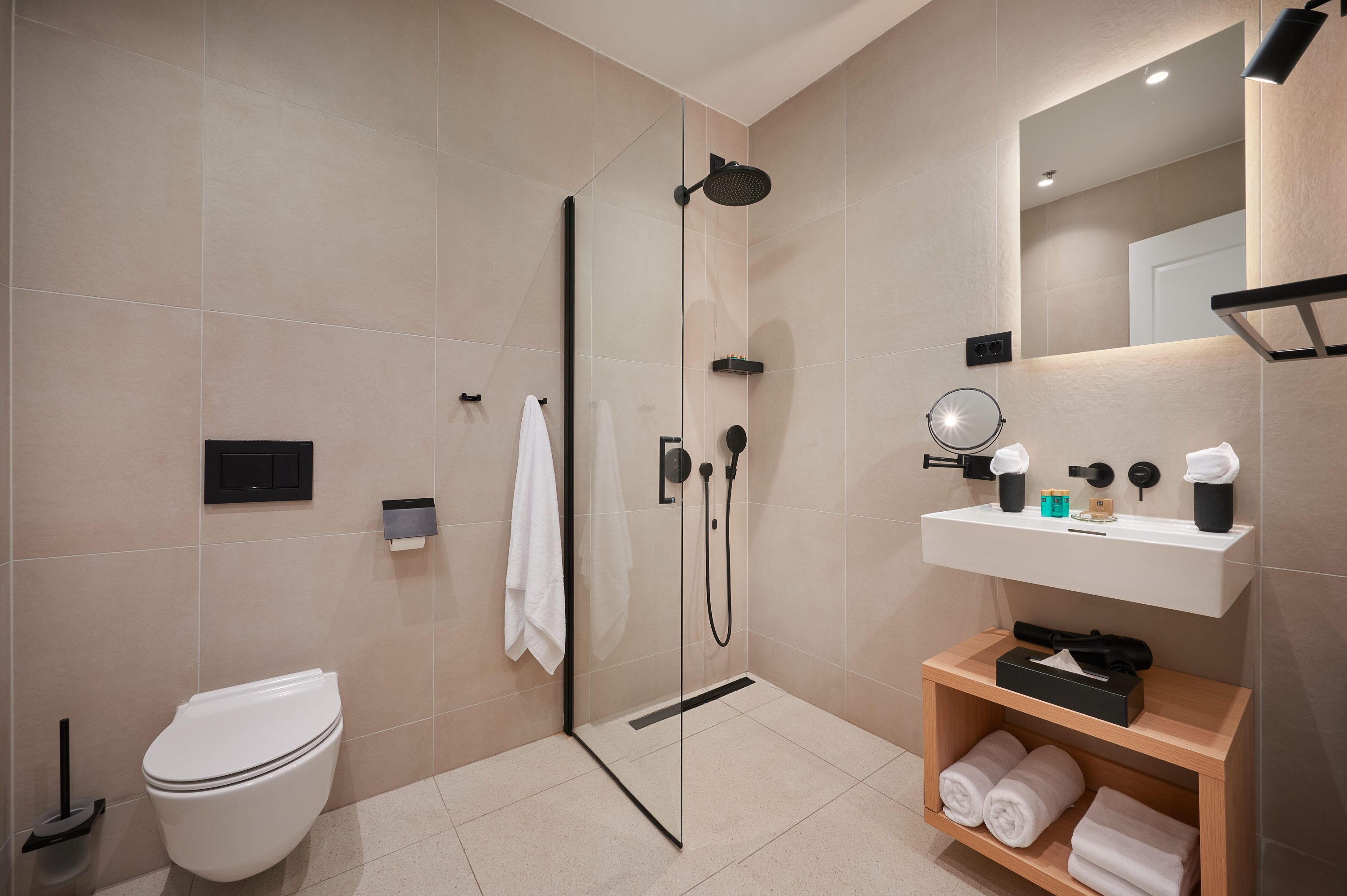 Un bagno moderno con doccia a vetro, un water bianco, un lavandino con articoli da toilette e un porta asciugamani.