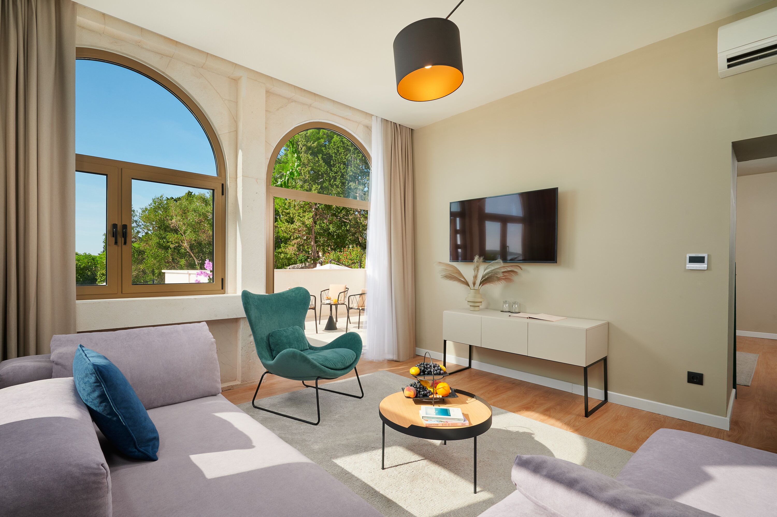 Ein modernes Wohnzimmer mit Sofa, Sessel, Couchtisch und Fernseher.