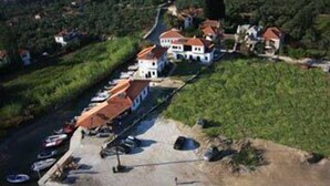 Vue aérienne d’une propriété située sur la côte, avec une rangée de maisons, une marina remplie de bateaux et un chemin de terre menant aux maisons.