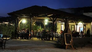 Un espace de restauration en plein air doté d’un pavillon couvert, de tables, de chaises et de quelques personnes assises.