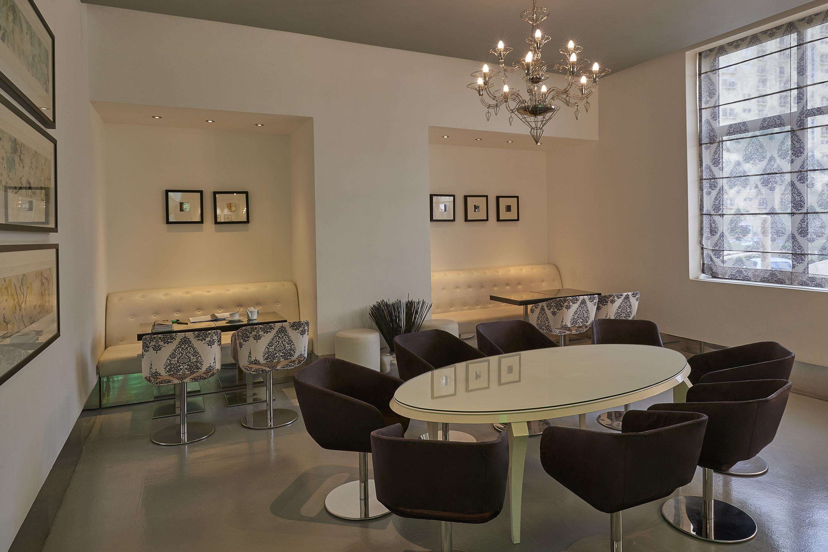A modern dining area with a round table and black chairs, a white sofa, and a chandelier.