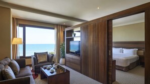 A hotel room with a large window, a sofa, a coffee table, a TV, and a bed. - Safir Fintas Kuwait Hotel (Fintas)