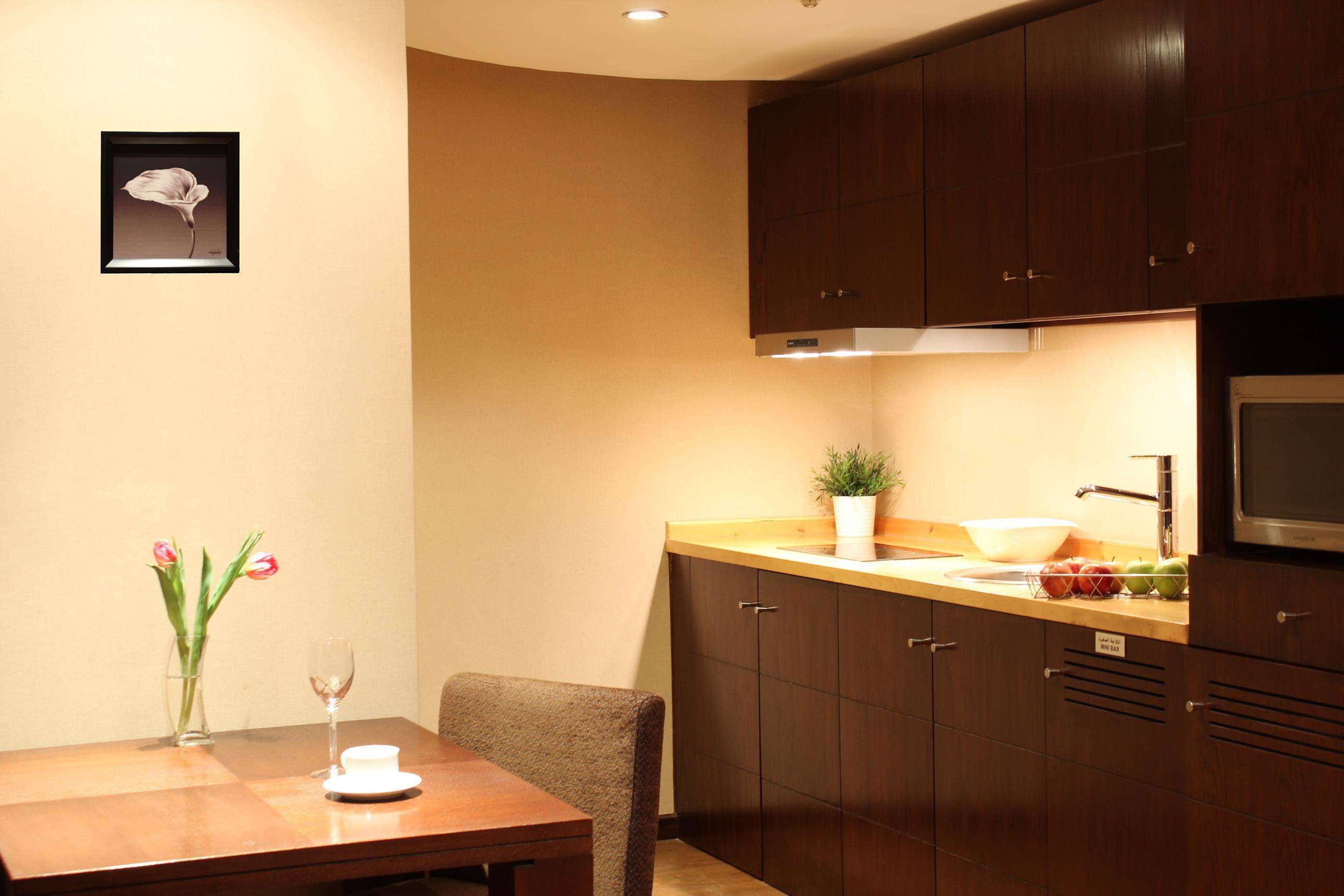 A modern kitchen with wooden cabinets, a dining table, and a vase with flowers.