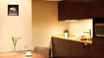 A modern kitchen with wooden cabinets, a dining table, and a vase with flowers.