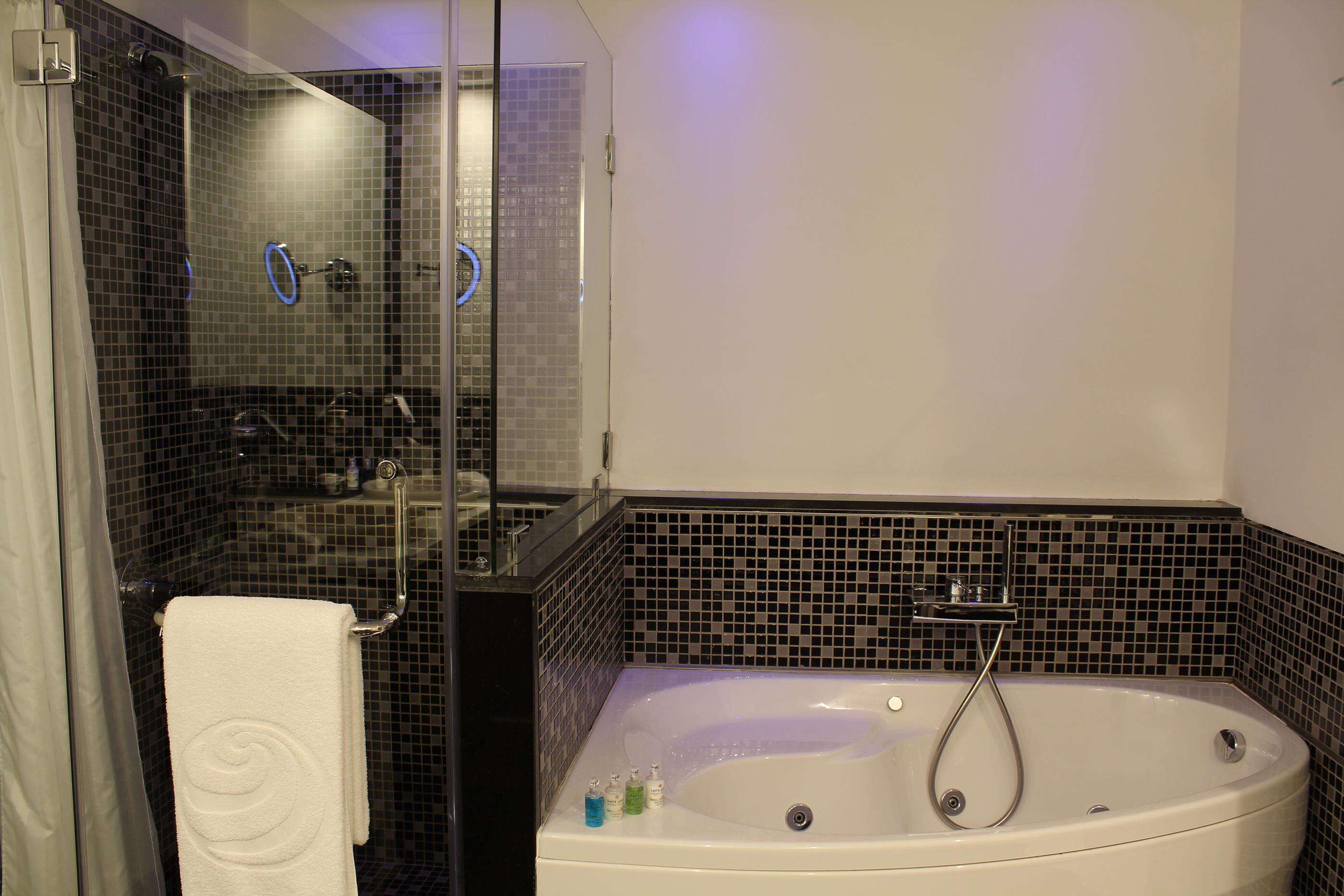 A bathroom with a glass-enclosed shower, a white bathtub, and a white towel hanging on a rack.