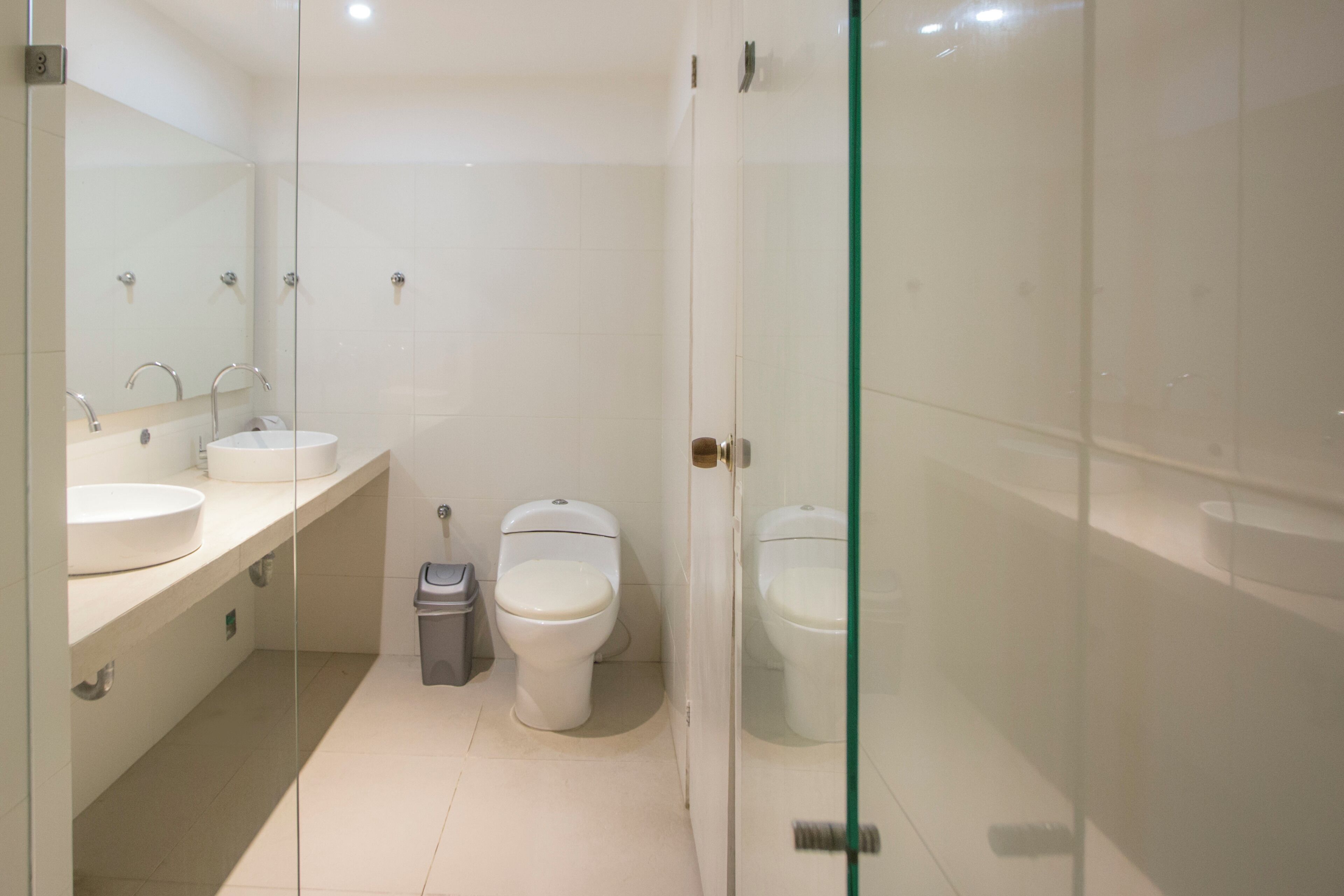 A modern bathroom with a glass shower enclosure, a sink, and two toilets.