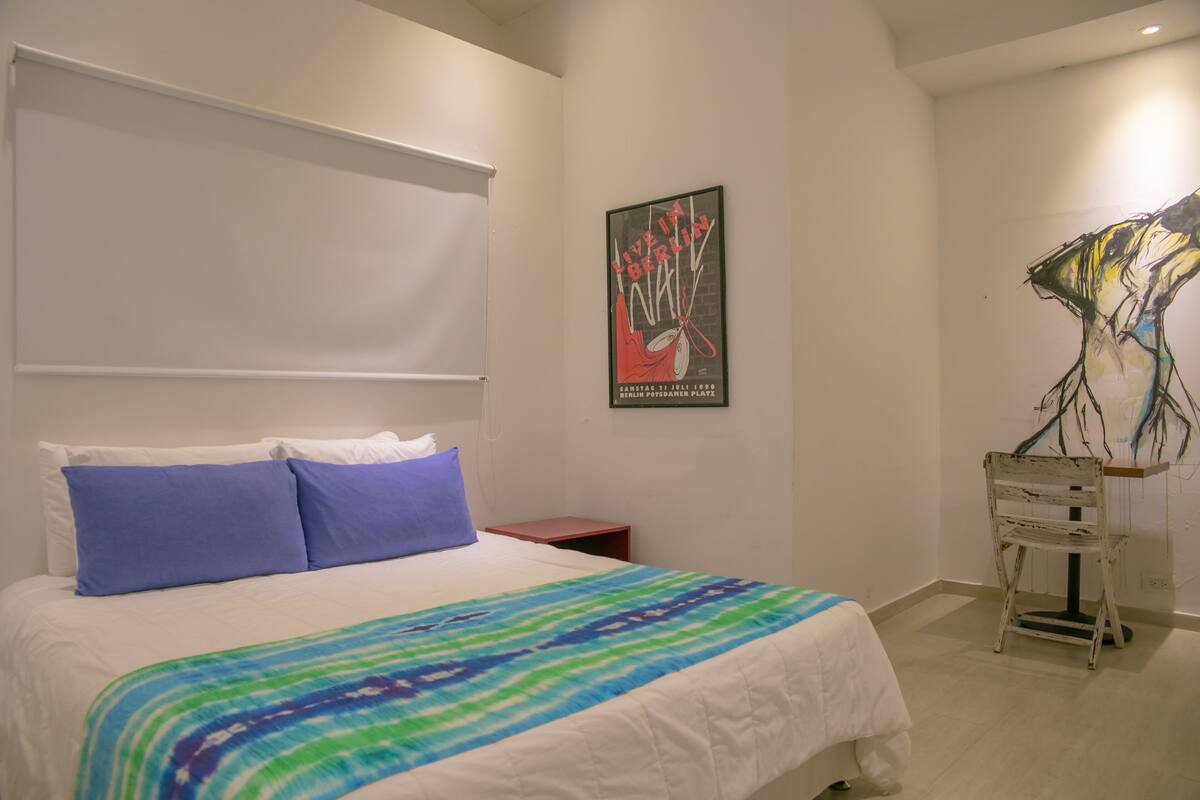 A bedroom with a bed, pillows, a poster, and a chair.