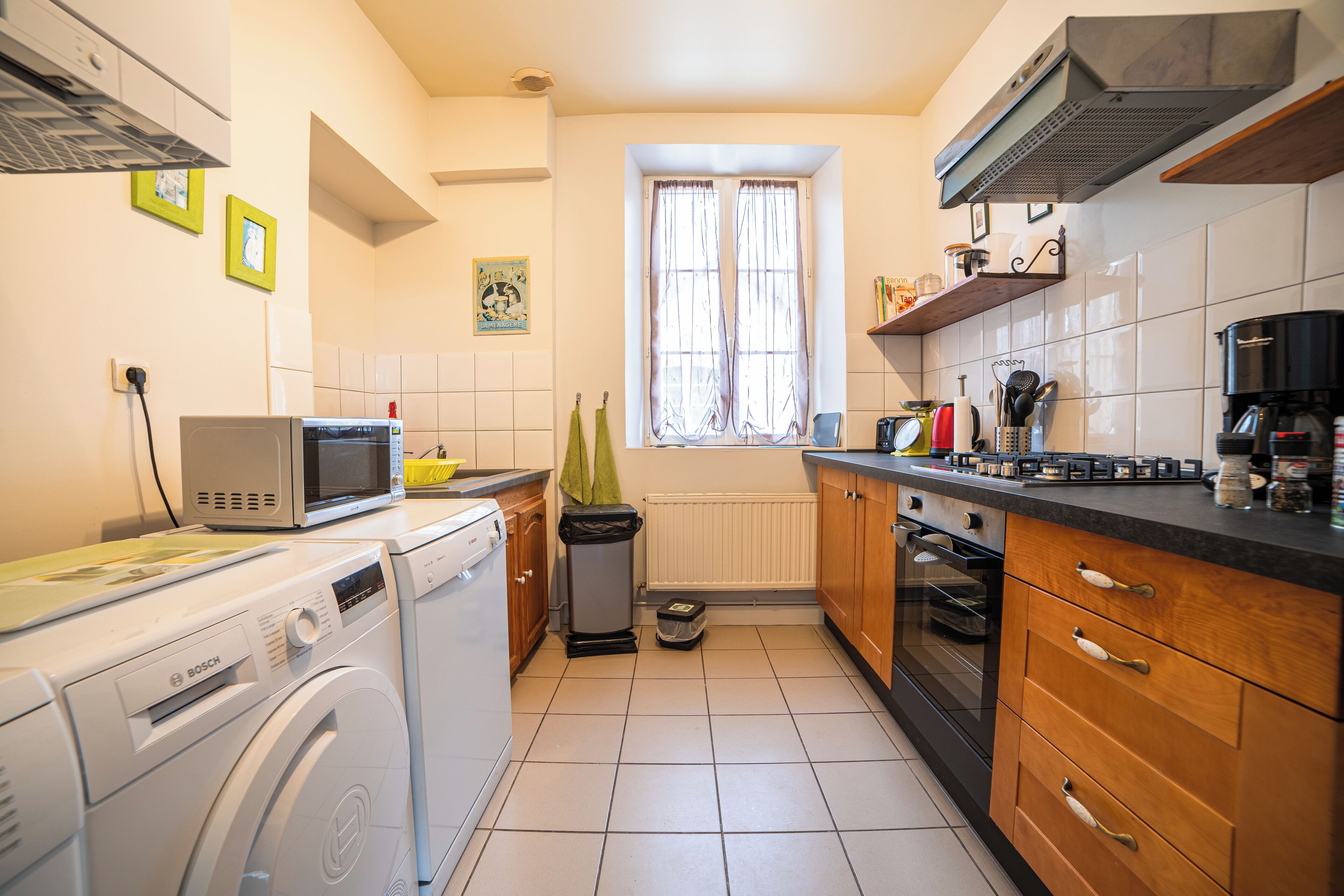 Eine kleine Küche mit Waschmaschine, Mikrowelle und Backofen.