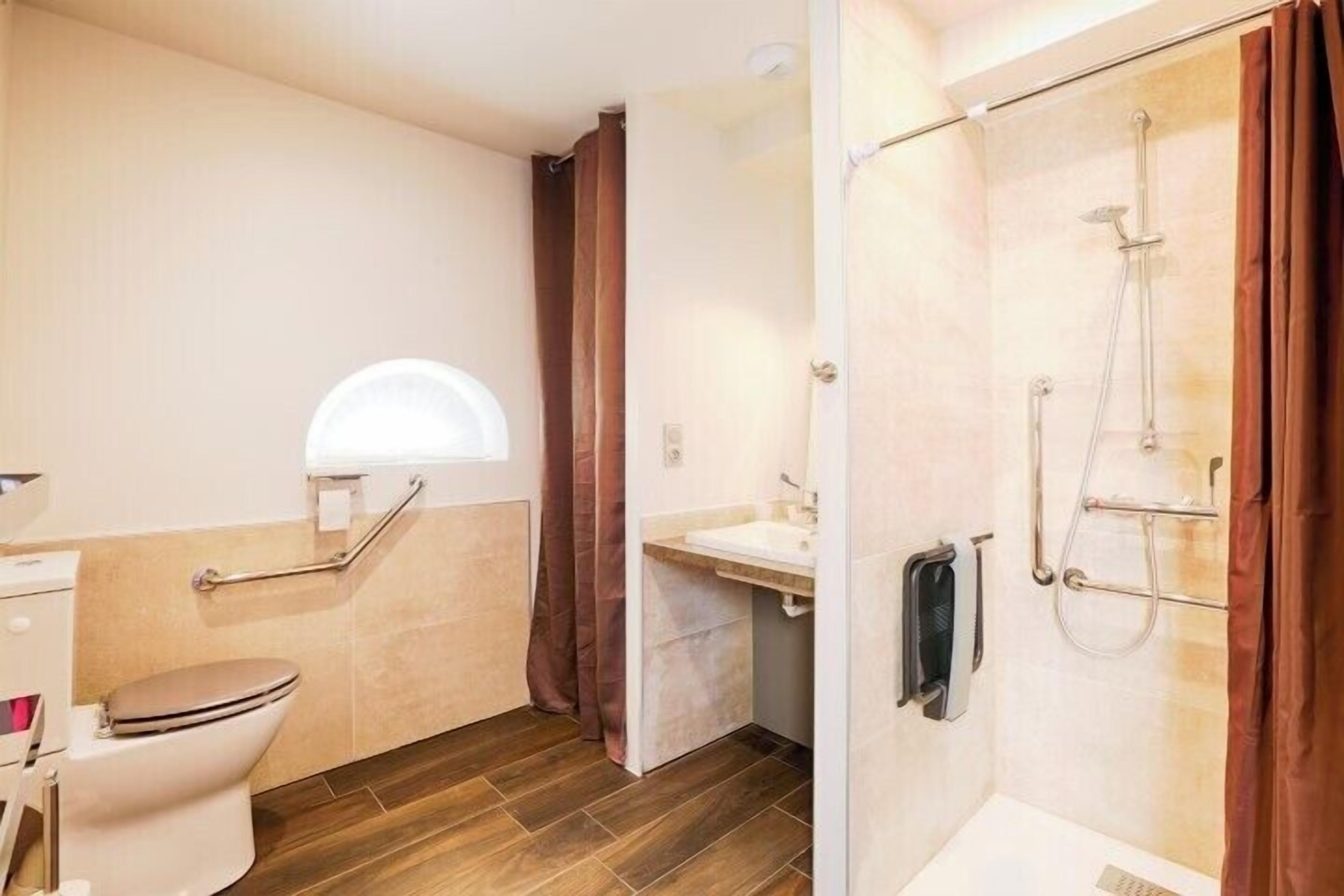 Un baño con inodoro, lavamanos, ducha y ventana.