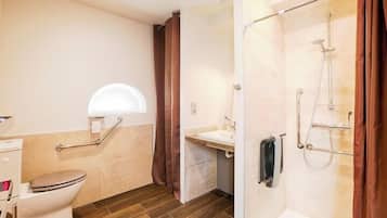 Un baño con inodoro, lavamanos, ducha y ventana.