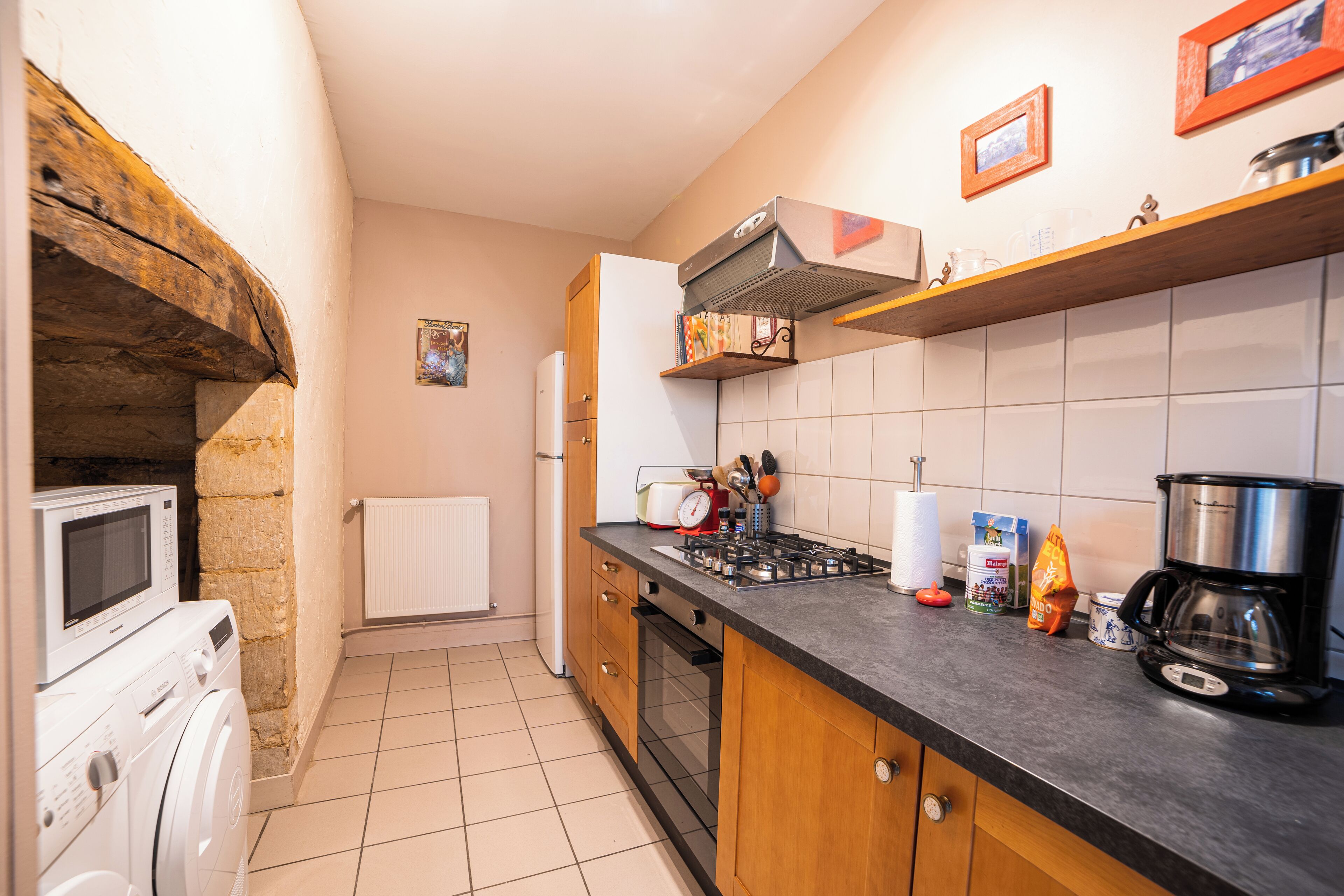 Cocina compacta con horno empotrado, microondas, cocina a gas y cafetera.