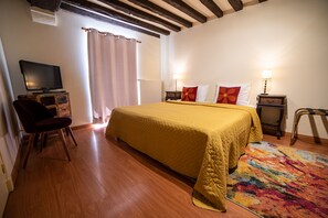 A hotel room with a bed, a chair, a television, and a window with curtains.