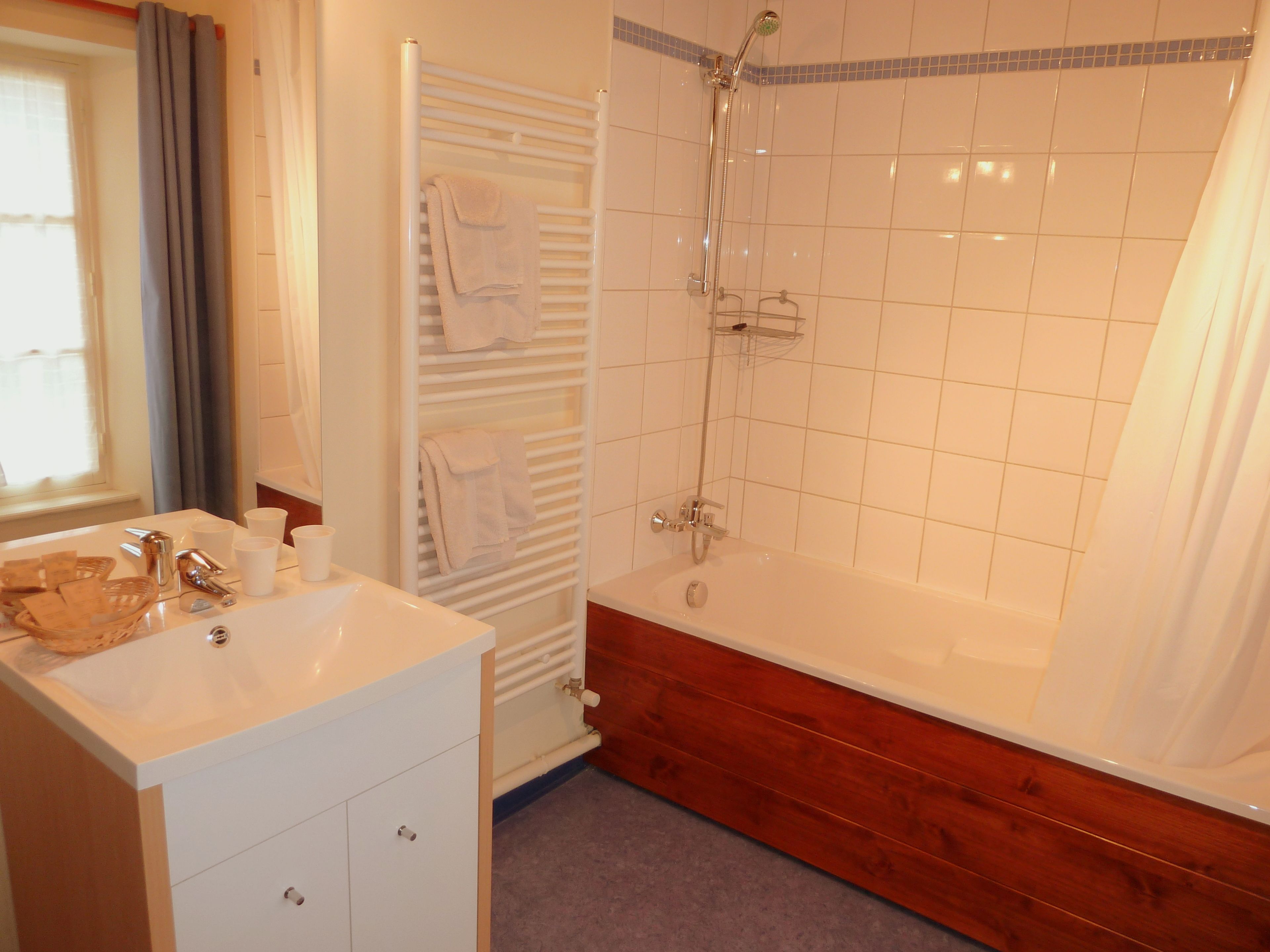A bathroom with a white sink, wooden vanity, a bathtub, and a shower.