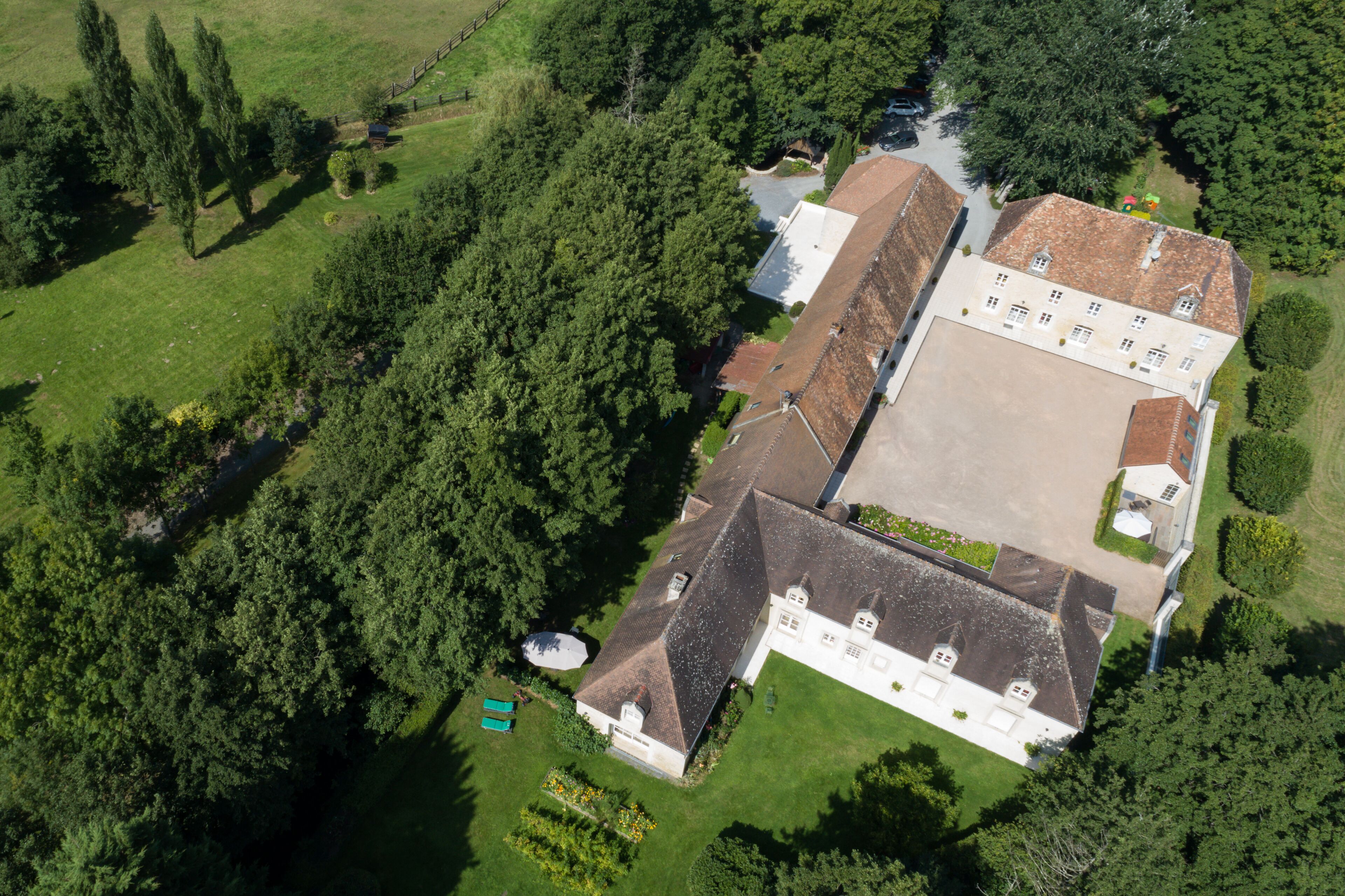An aerial view of a large estate with multiple buildings, extensive greenery, and a well-maintained lawn.