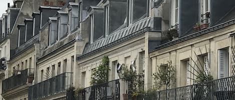 Una hilera de edificios históricos con arquitectura europea clásica, que presenta tejados mansard y balcones ornamentales.