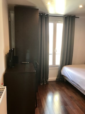 Habitación de hotel con cama, escritorio y ventana con cortinas.