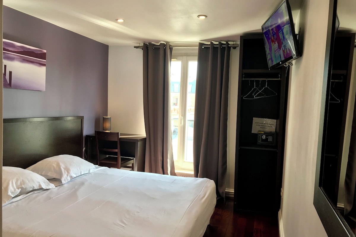A hotel room with a bed, a desk, a television, and a wardrobe.