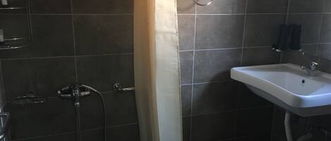 A bathroom with a shower, a sink, and a towel ring.