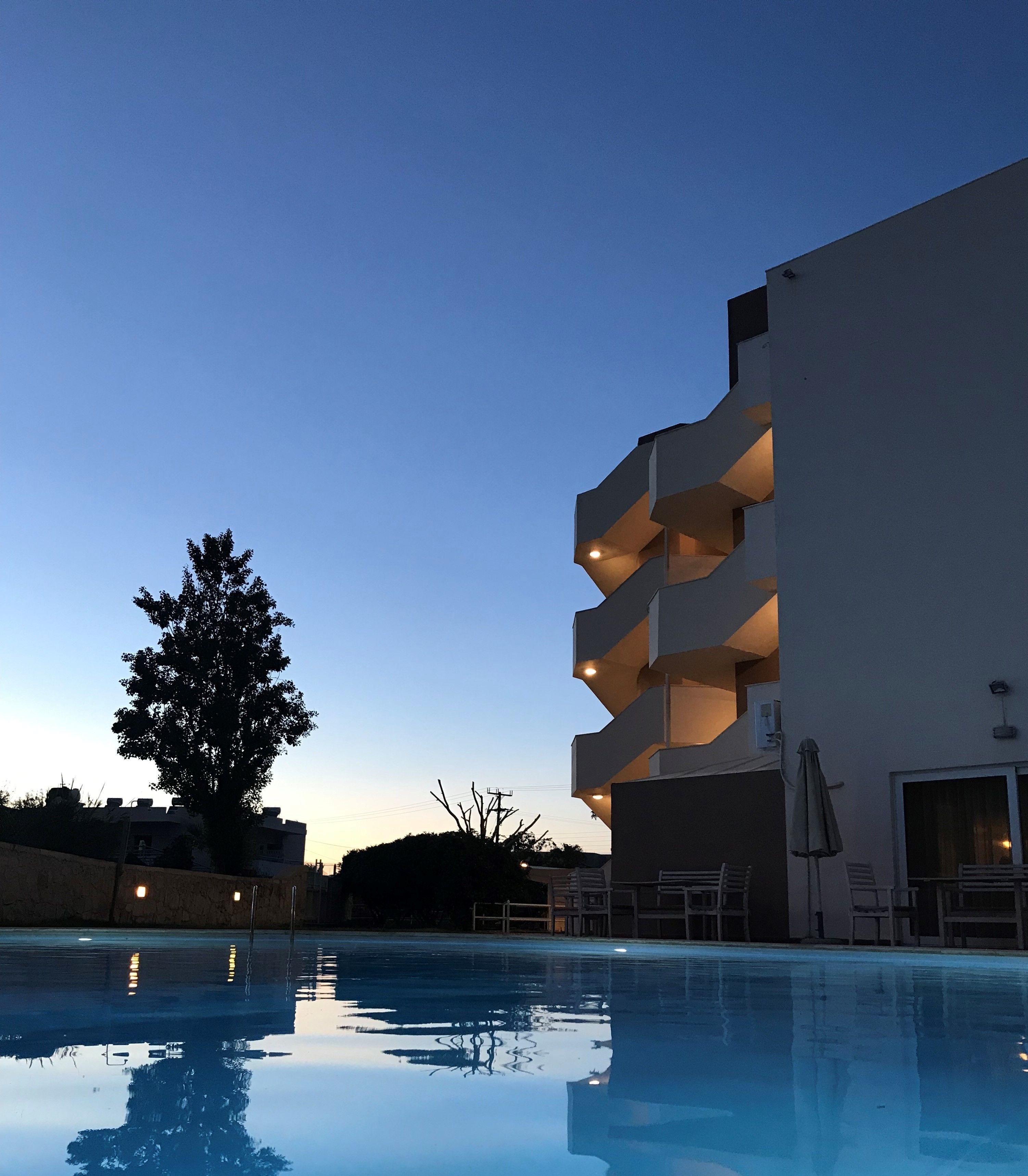 Un edificio moderno con varios balcones que dan a una piscina.