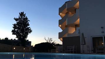Un edificio moderno con varios balcones que dan a una piscina.