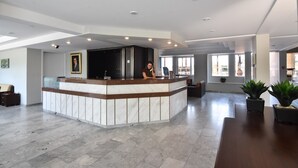 Um hall amplo com uma receção em mármore, uma janela grande e um design de teto moderno.