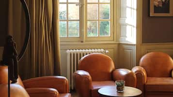Ein Zimmer mit großem Fenster, Ledersesseln, einem kleinen Tisch und einem Heizkörper.