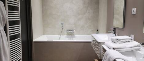 A modern bathroom with a bathtub, a sink, and a towel rack.