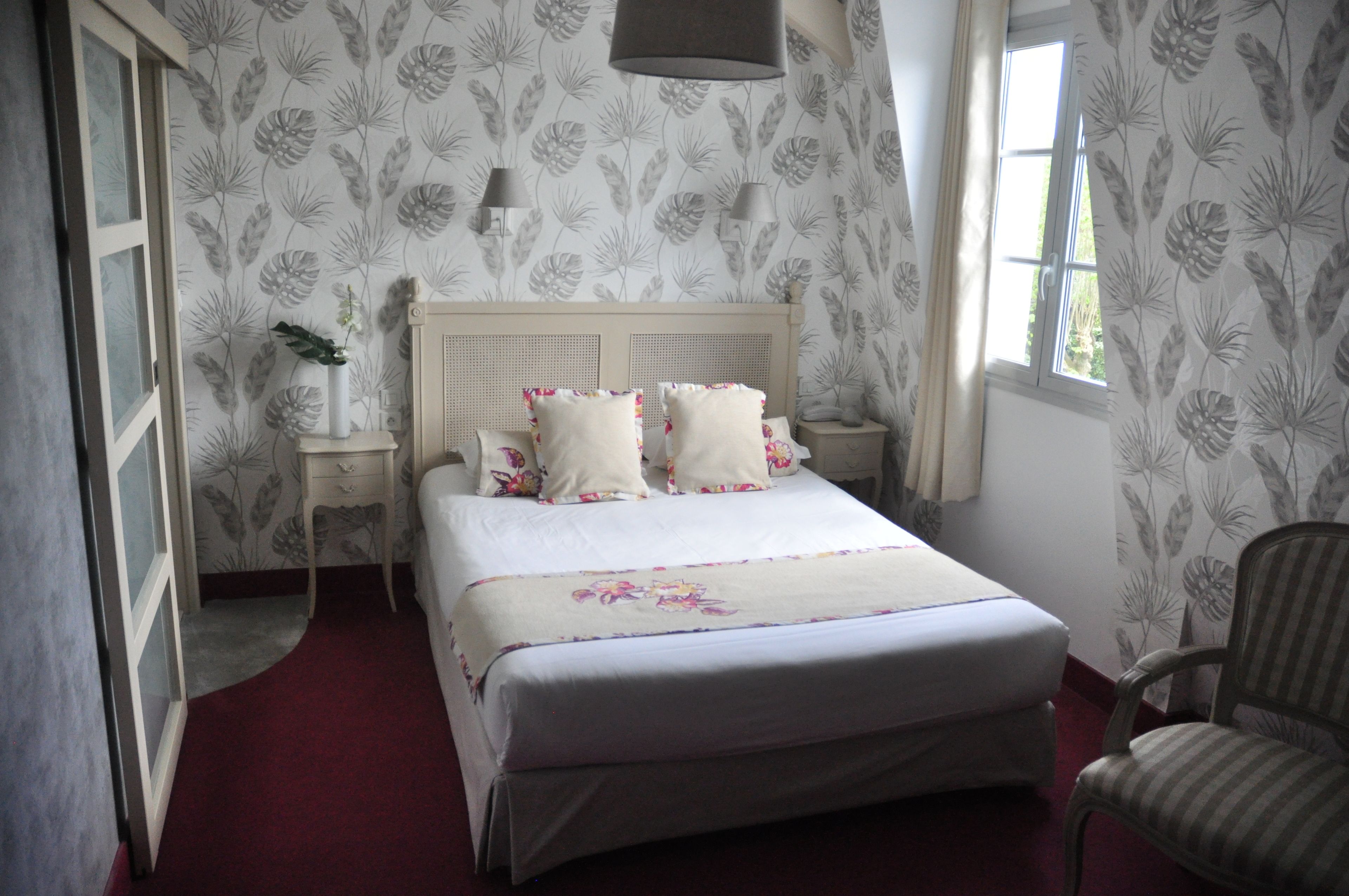 A bedroom with a bed, nightstands, a chair, and a window.