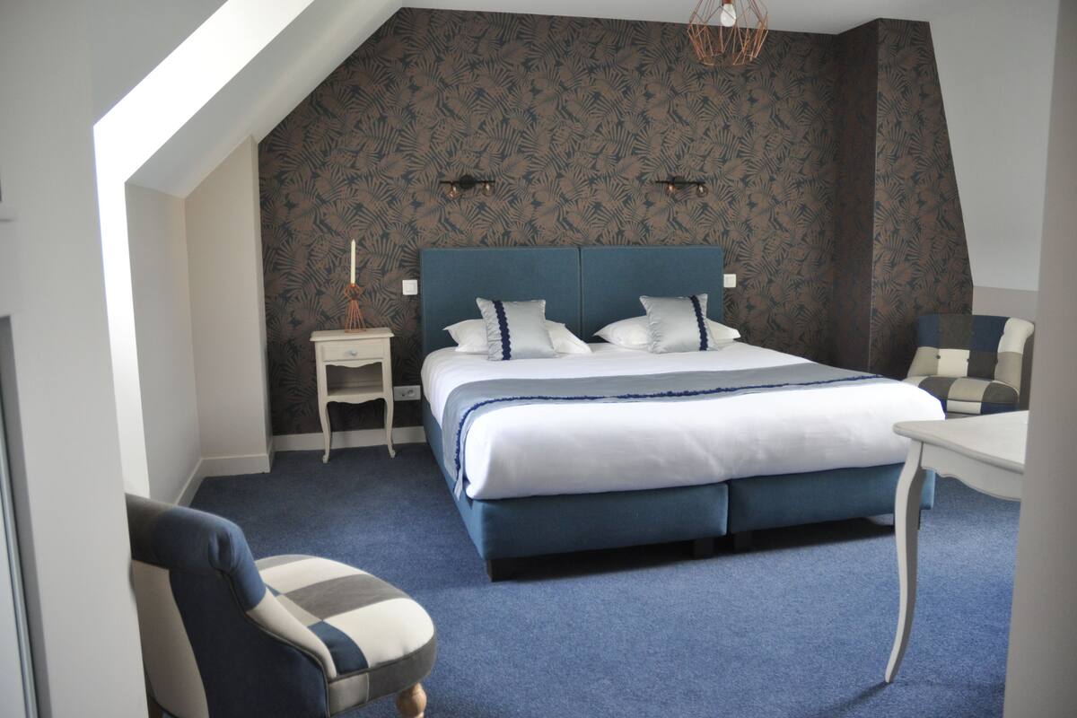 Une chambre à coucher avec un grand lit, une table de chevet, une chaise et une petite table.