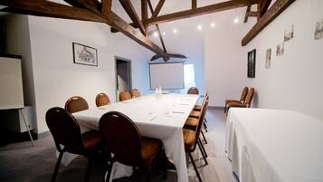 A conference room with a long table, chairs, a projector screen, and a whiteboard.