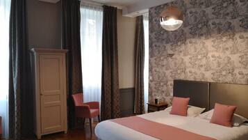 Una habitación de hotel con una cama grande, un armario, una silla y una mesita de noche.