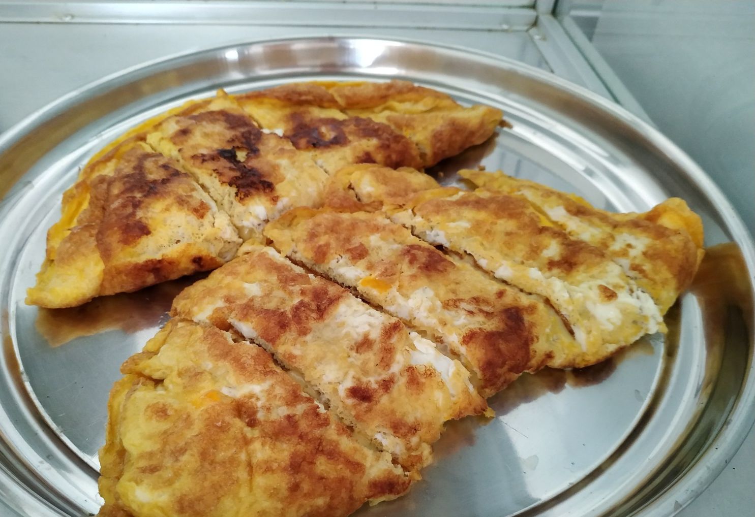 A metal tray with several pieces of food, possibly a type of stuffed bread or pastry, arranged on it.