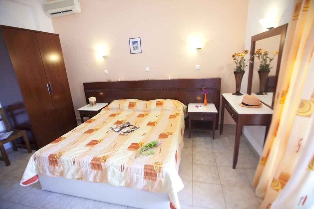 A hotel room with a bed, bedside tables, a wardrobe, and a mirror.