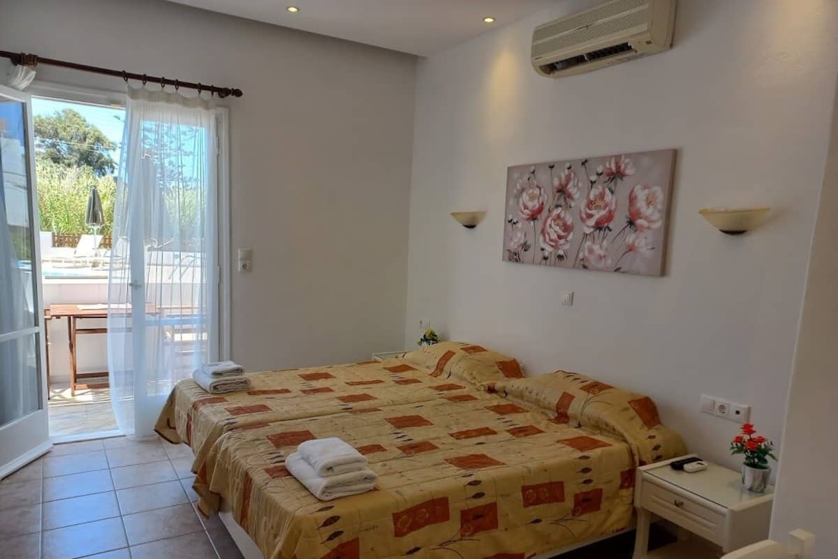 A hotel room with two beds, a desk, a chair, and a painting on the wall.