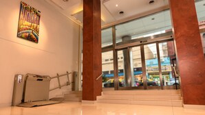 A clean, modern lobby with a glass entrance, a staircase, and a decorative wall piece. - Icaro Suites (Buenos Aires)