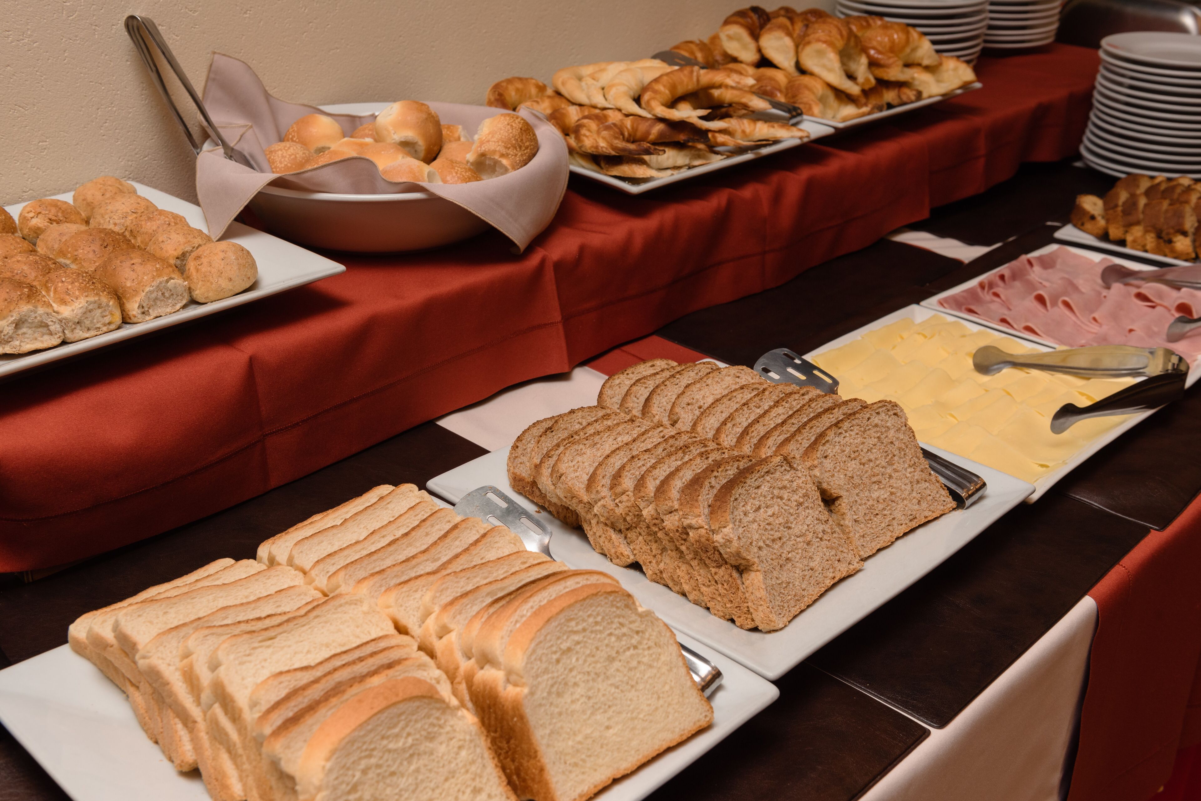 Una mesa de buffet con diferentes tipos de comida, incluyendo pan, pasteles y queso.