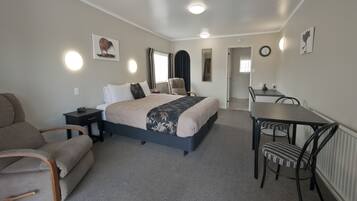 A hotel room with a bed, a desk, a chair, a sofa, and a mirror.
