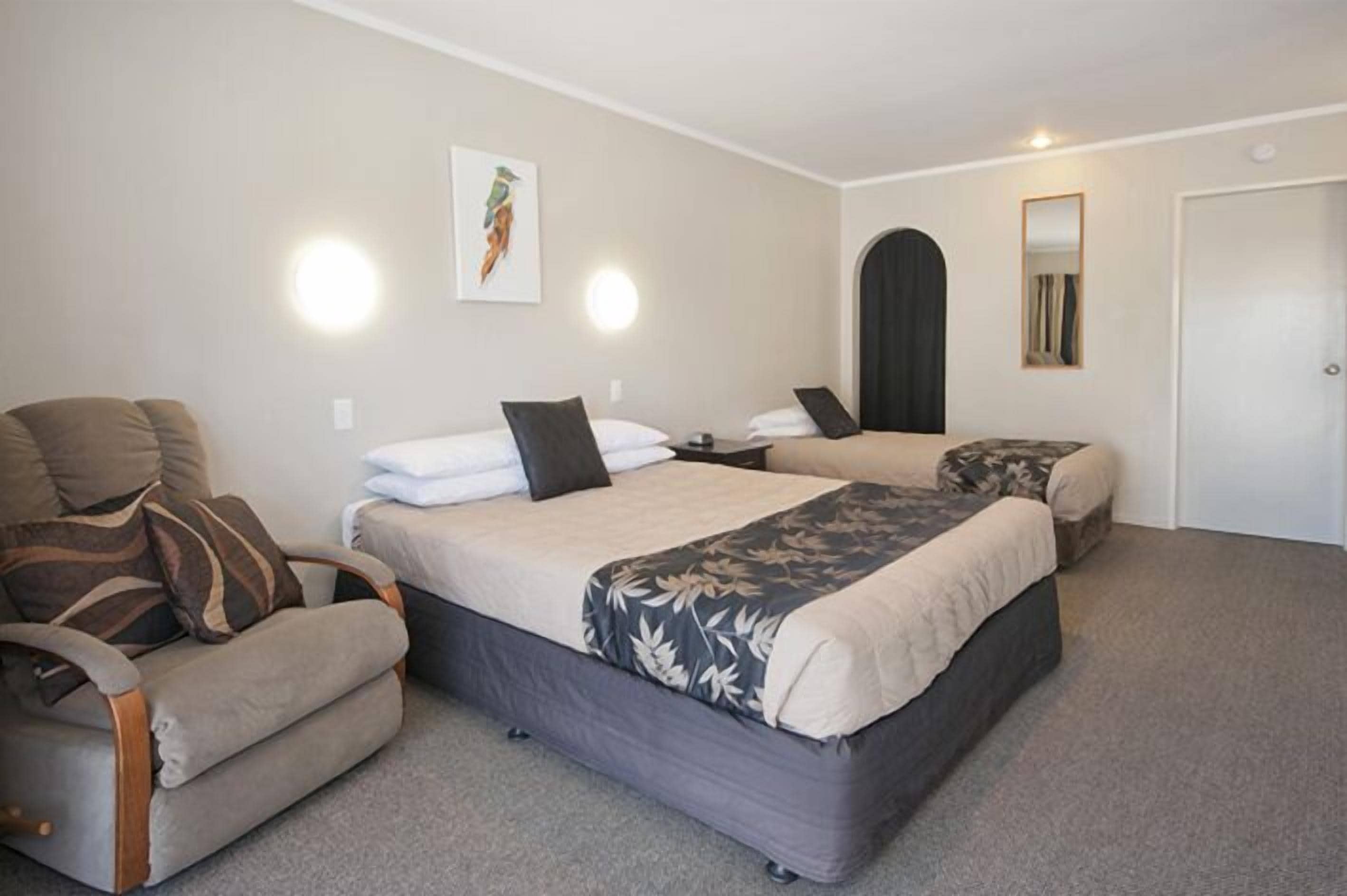 Ett hotellrum med två sängar, en soffa och en spegel.